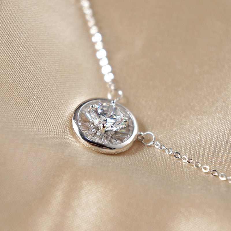 Silver-tone circle pendant with zircon stone resting on champagne satin