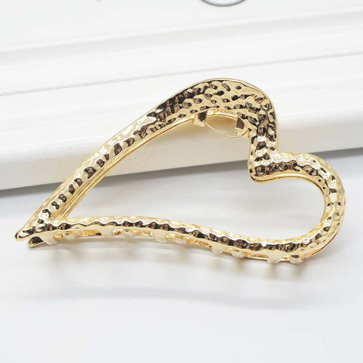 Gold-tone open heart claw clip with a hammered-look texture