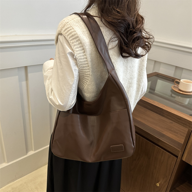 Back view of a woman carrying the brown slouchy shoulder bag on her shoulder