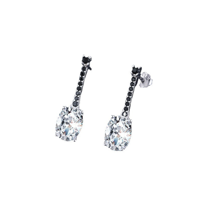 Silver-tone drop earrings with a clear oval zircon below a bar of tiny black stones, white background