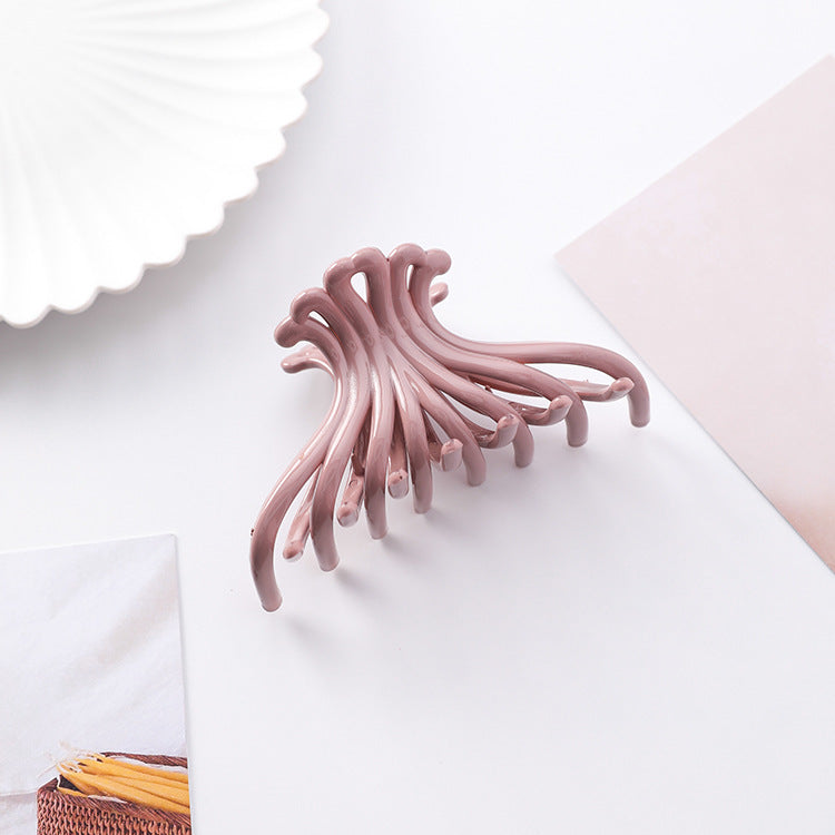 Dusty pink wave hair claw clip on a white styled surface