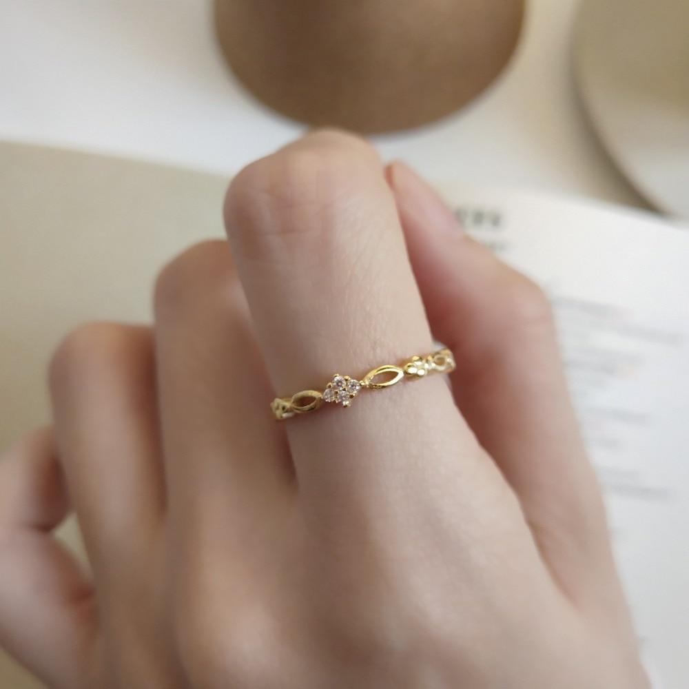Gold-tone open ring with zircon-style stone worn on a finger
