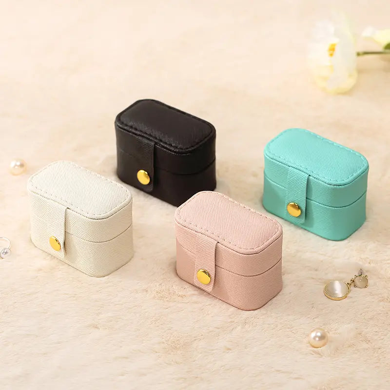 Closed mini ring travel cases in black, cream, pink and aqua