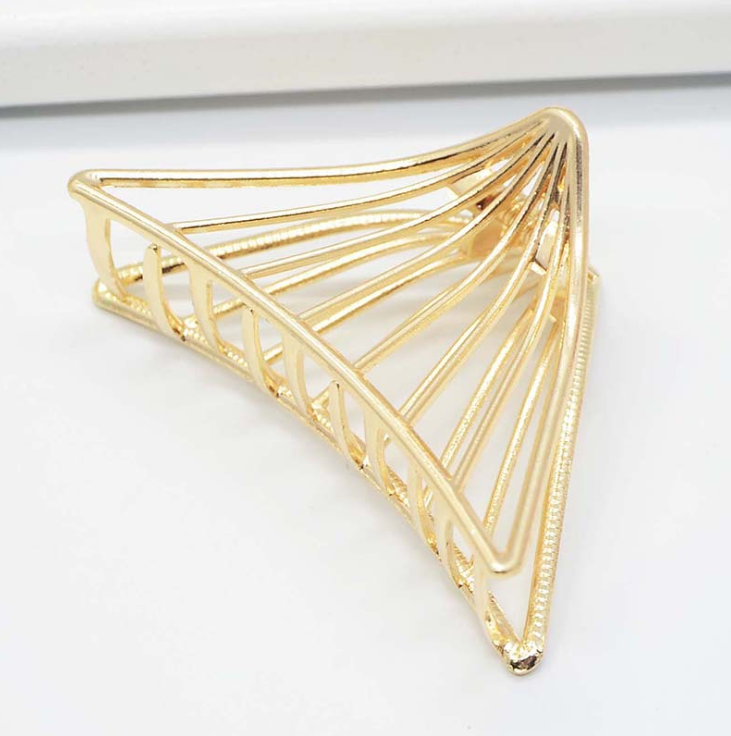 Gold-tone triangle claw clip with radiating wire lines, on a white surface