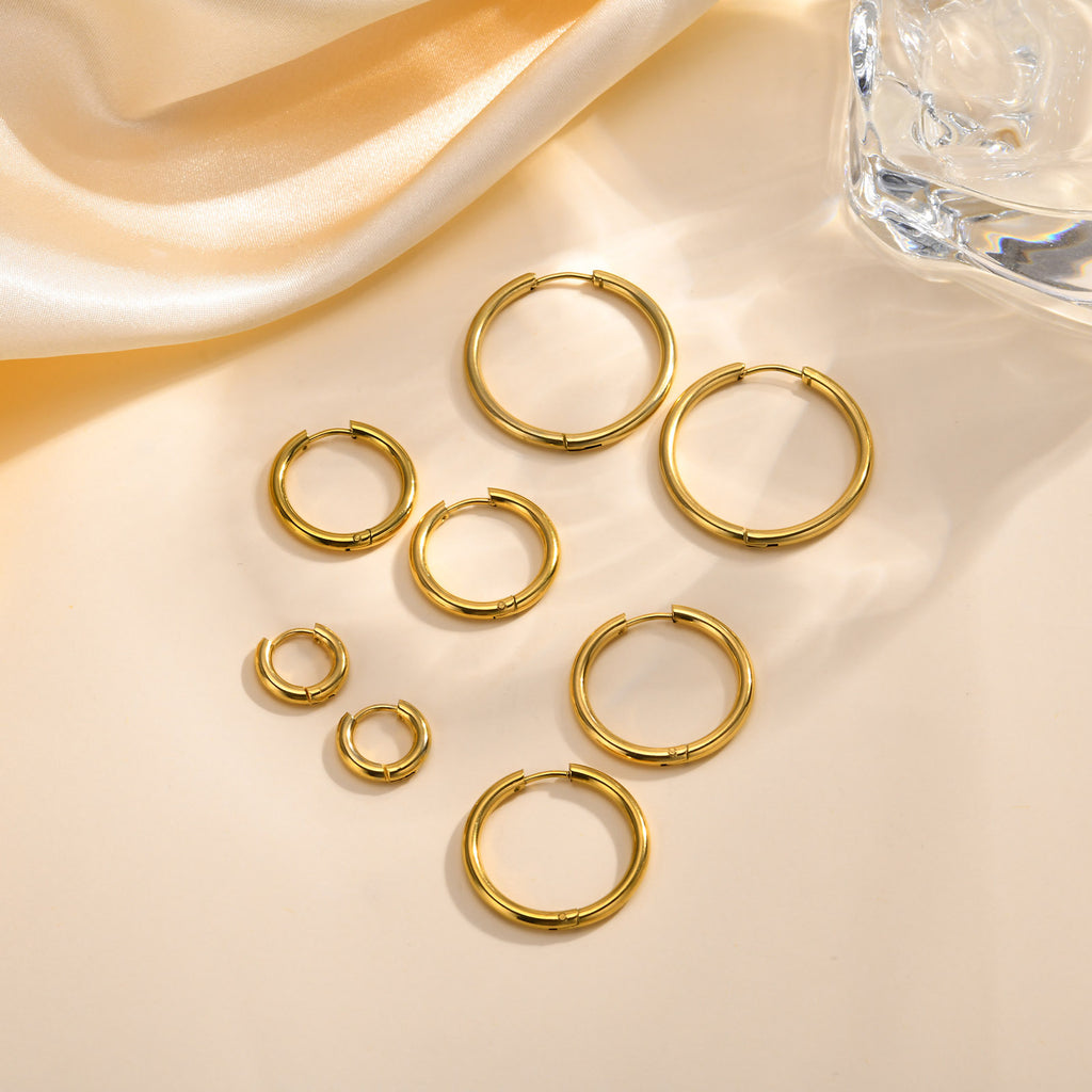 Gold-tone huggie hoop earrings in four graduated sizes on cream satin