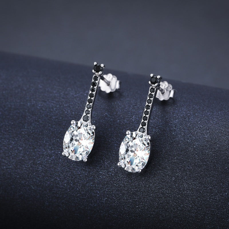 Silver-tone oval zircon bar drop earrings with tiny black stones on a dark background