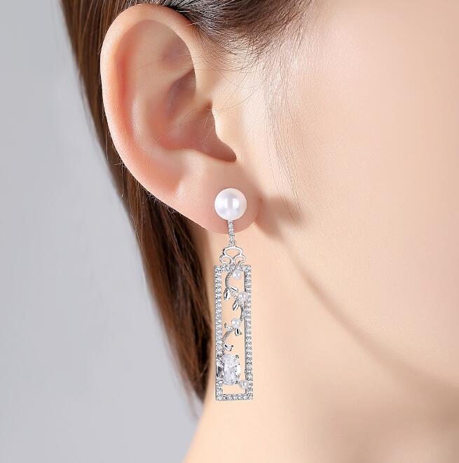 Silver-tone rectangular drop earring with pearl-style top, worn