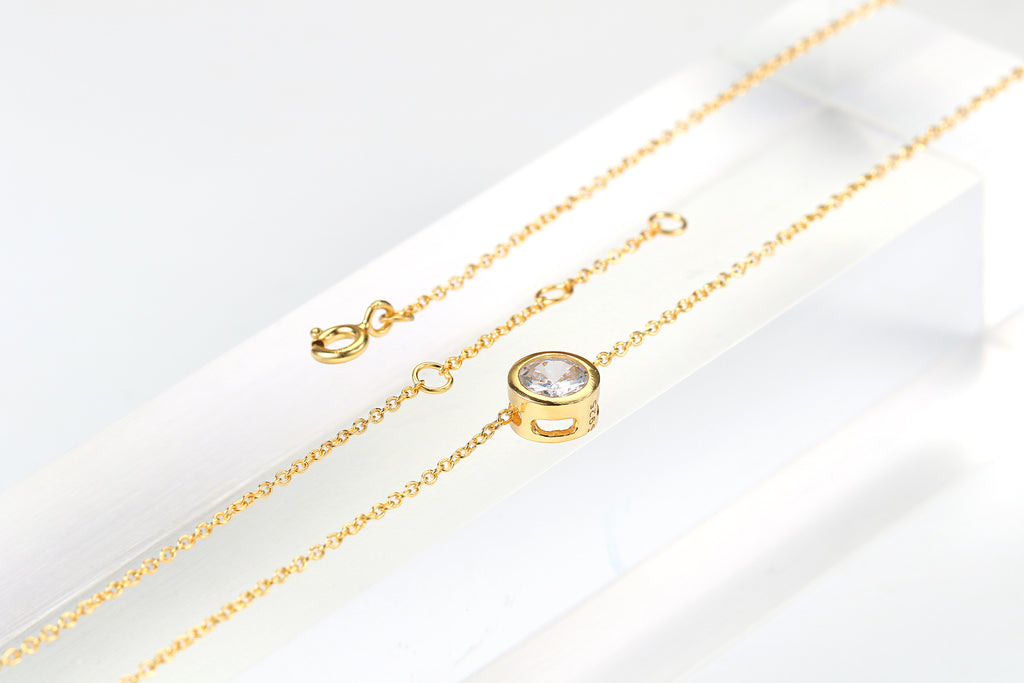 Gold-tone bezel zircon necklace on clear acrylic with clasp and extender chain