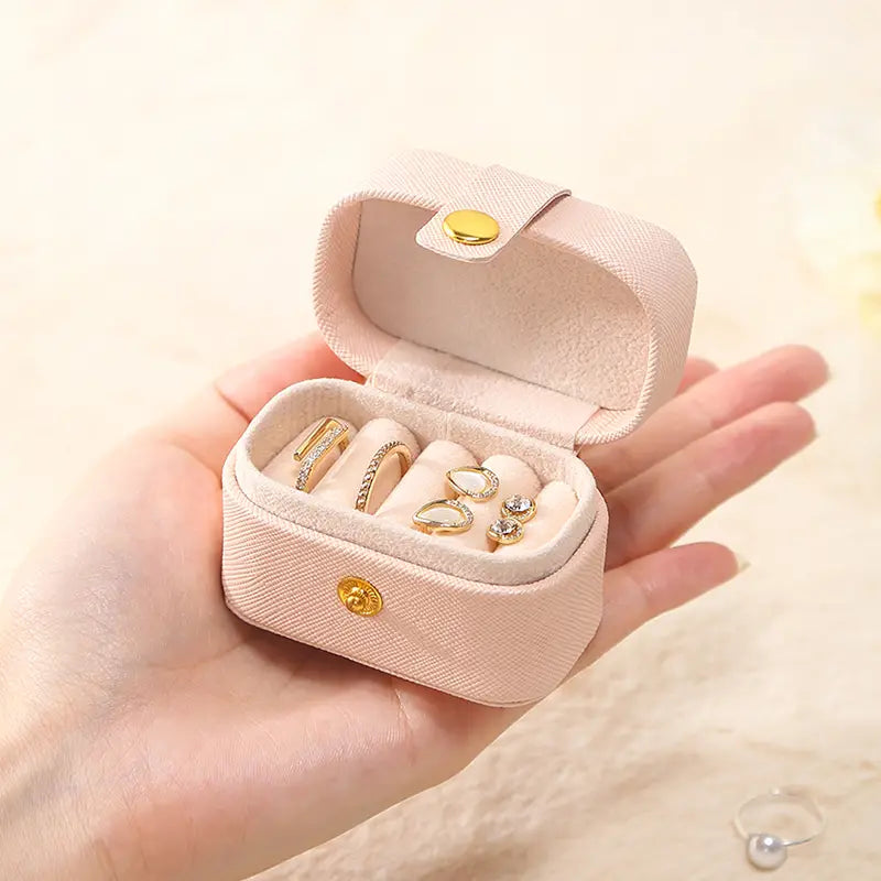 Pink mini ring travel case held in an open hand, rings inside