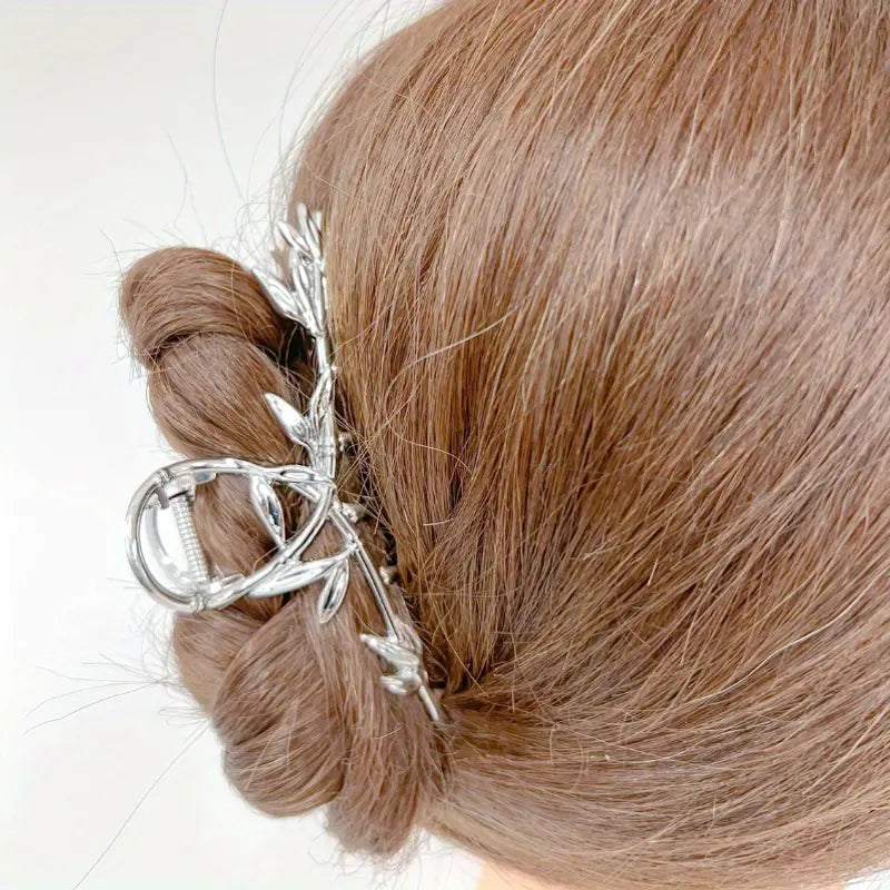 Silver-tone twig hair claw clip holding a low bun, side view