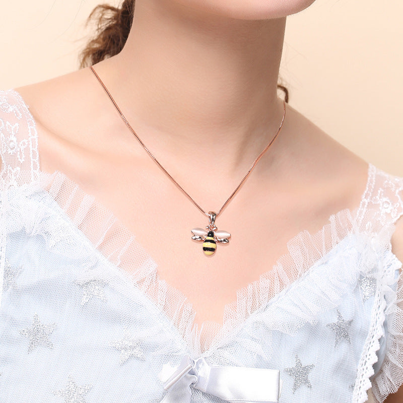 Rose gold-tone bee pendant necklace worn with a white lace top