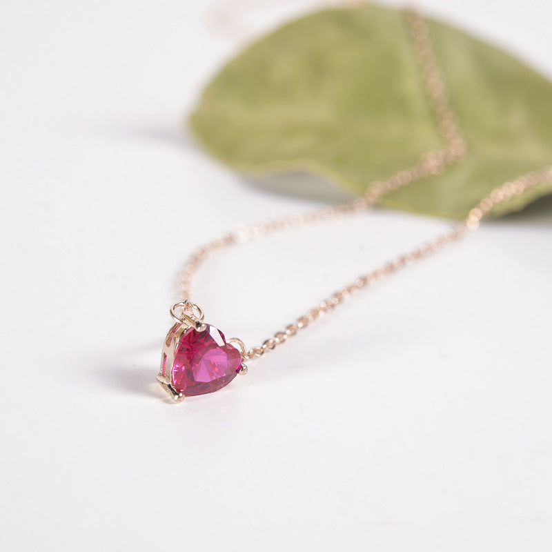 Close-up of a deep pink heart-shaped pendant on a rose gold-tone chain