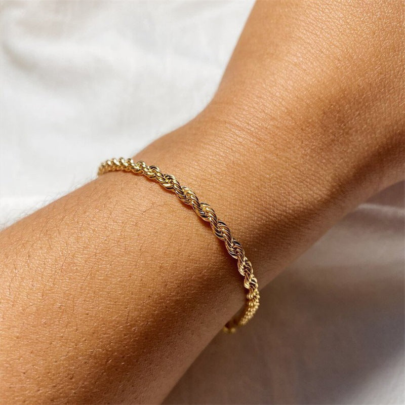 Gold-tone twisted rope chain bracelet worn on the wrist