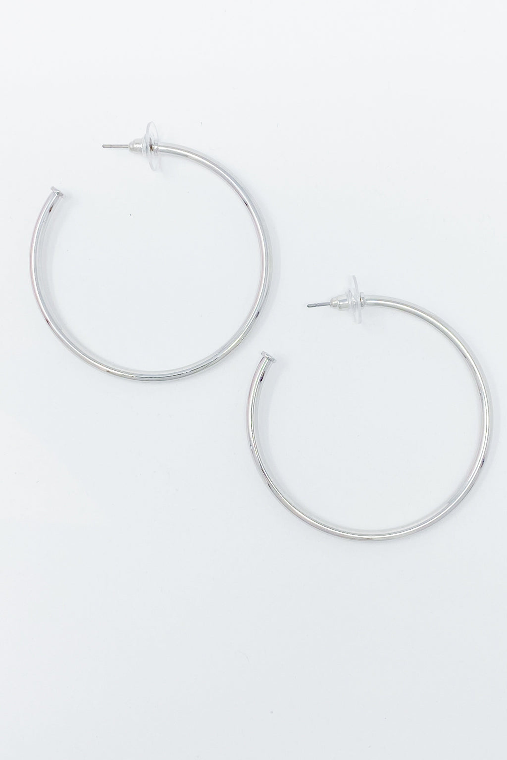 Pair of thin silver-tone hoop earrings on a light grey background