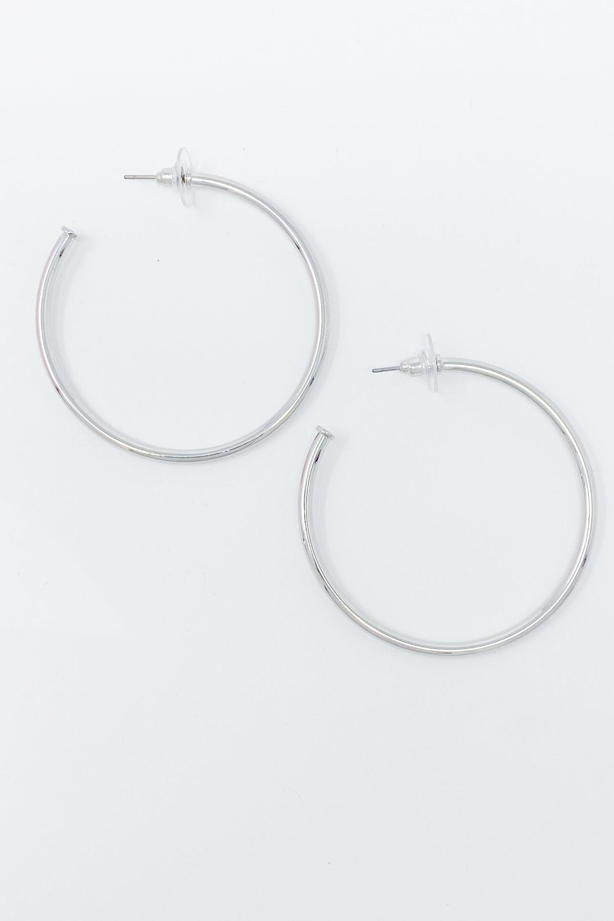 Pair of thin silver-tone hoop earrings on a light grey background