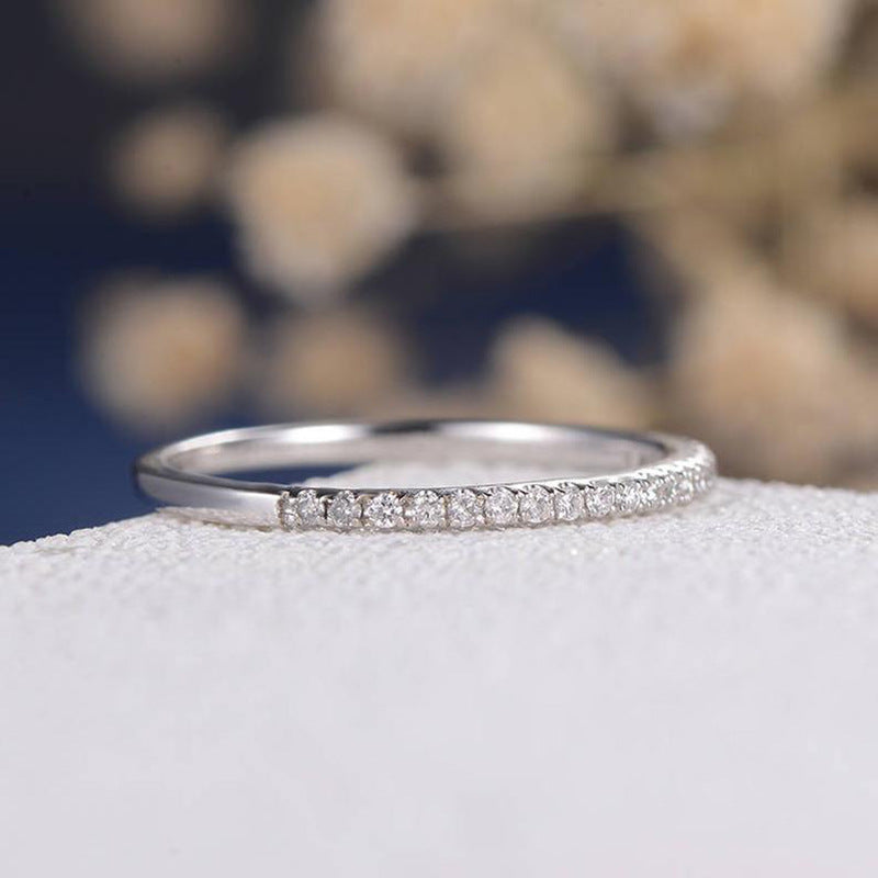 Silver-tone stacking band with a row of small zircon stones, side view on a white surface