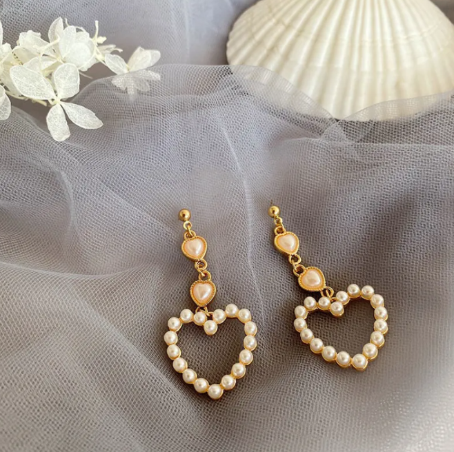 Pair of open heart drop earrings with pearl-style beads and a heart-shaped top on grey tulle