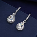 Silver-tone teardrop earrings with a clear zircon center and halo of small zircons, on navy fabric