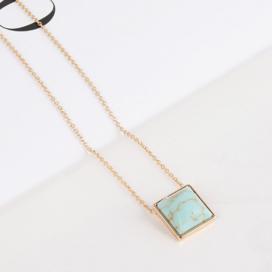Aqua square pendant with brown veining on a fine gold-tone chain, angled view