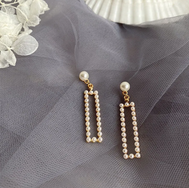 Pair of long rectangular drop earrings lined with pearl-style beads on grey tulle