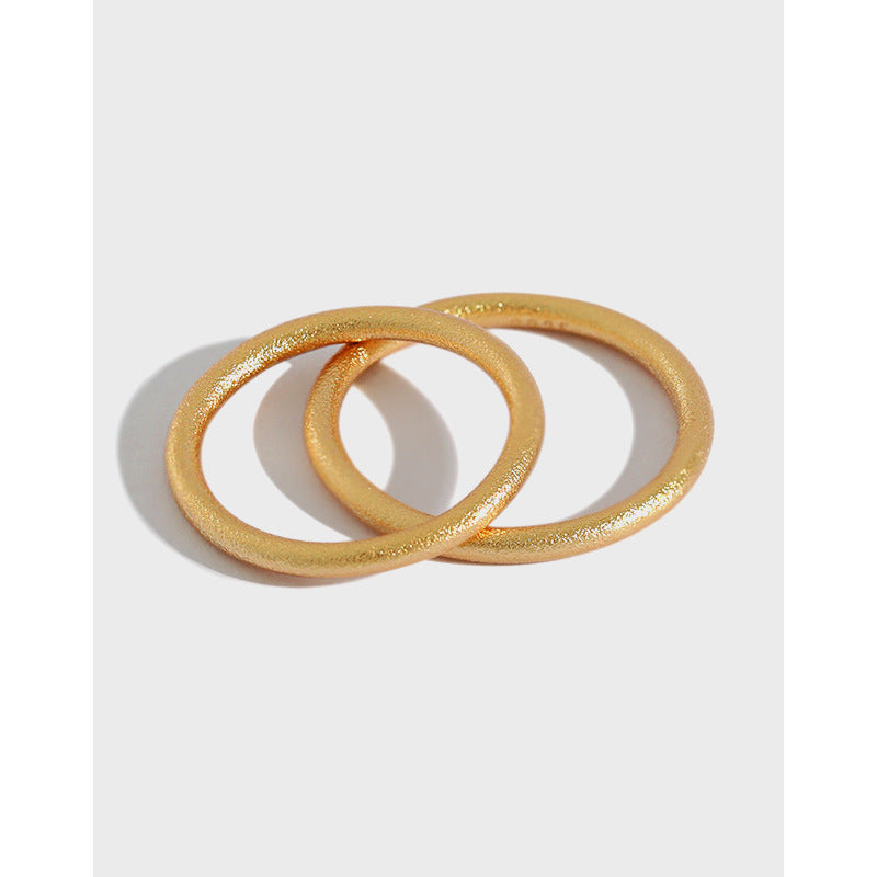 Two gold-tone textured stacking rings overlapping on a light grey background