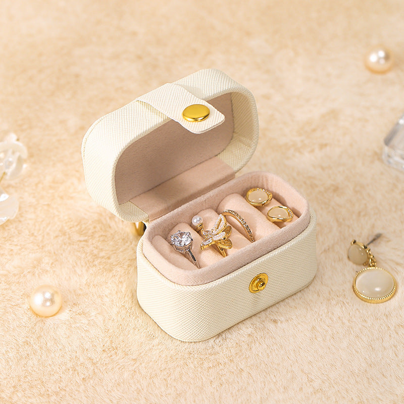Cream mini ring travel case, open with gold-tone and silver-tone rings