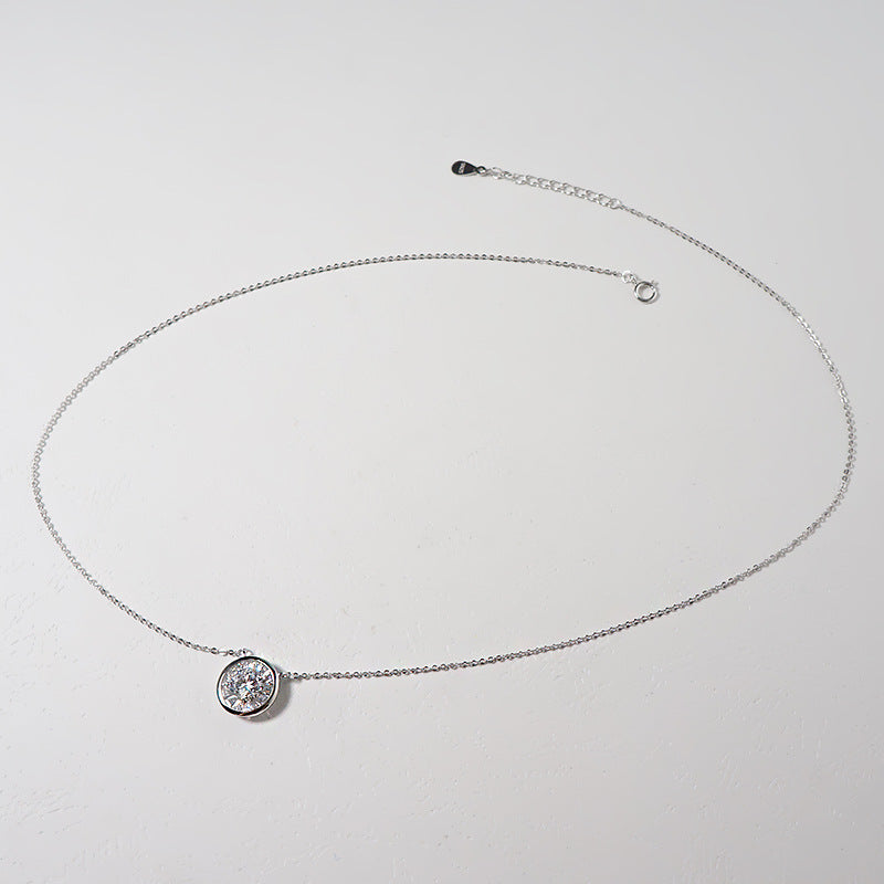 Silver-tone circle pendant necklace laid flat on a light grey surface, extension chain visible