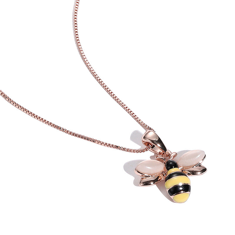Close-up of a rose gold-tone bee pendant with yellow and black stripes and pale wings