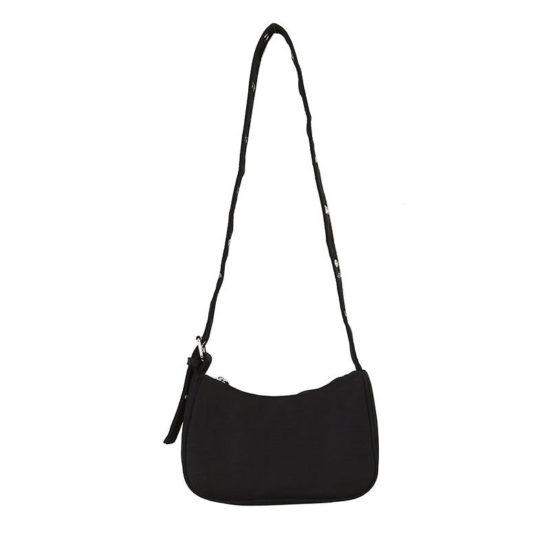 Black shoulder bag with a long eyelet strap and zip top, shown on a plain white background