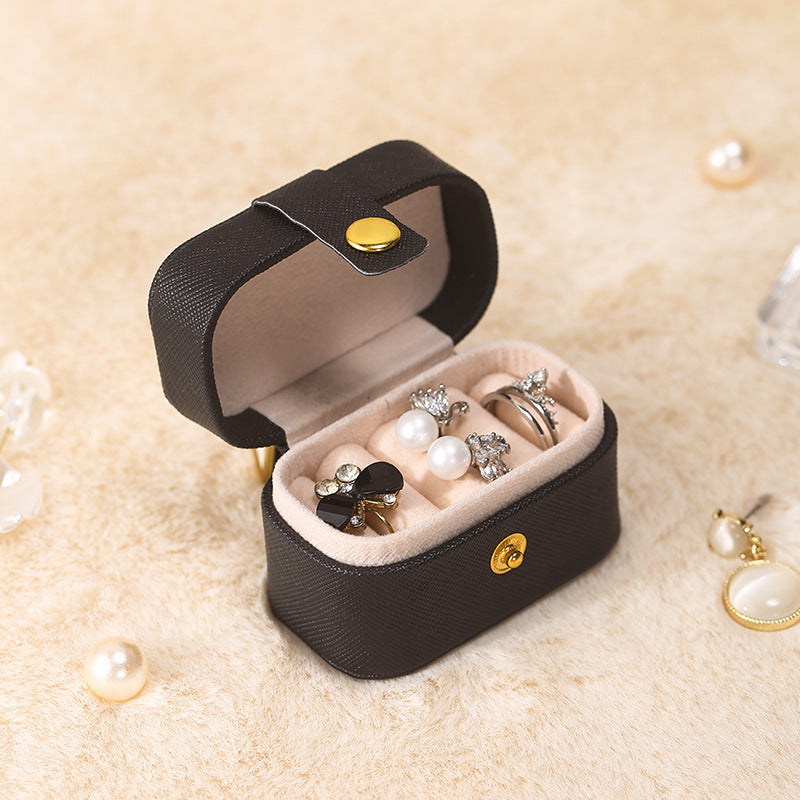 Black mini ring travel case, open with rings, one with a pearl-style bead