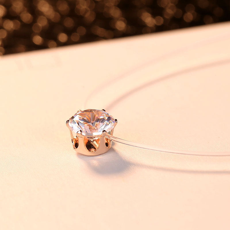 Angled view of the rose gold-tone setting of a zircon pendant on a clear cord