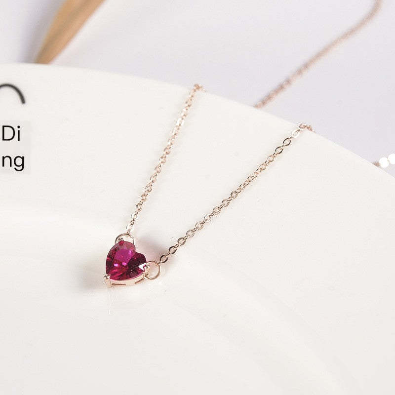 Pink heart-shaped pendant on a rose gold-tone chain resting on a white plate