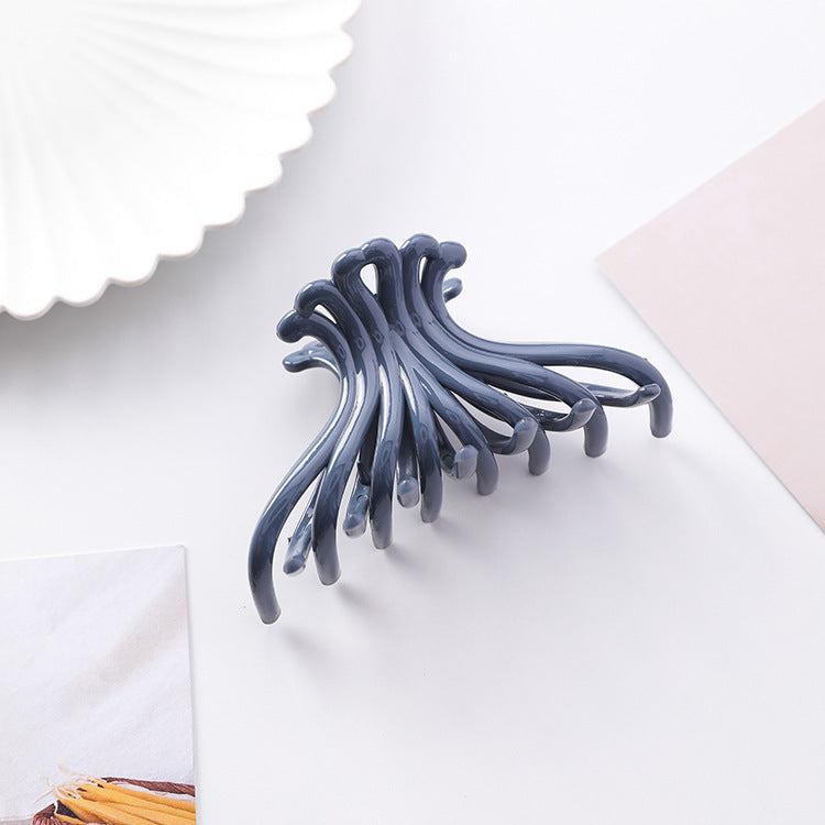 Navy blue wave hair claw clip on a white styled surface