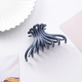 Navy blue wave hair claw clip on a white styled surface
