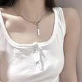 Silver-tone chain necklace with toggle clasp and flat bar pendant, worn with a white top