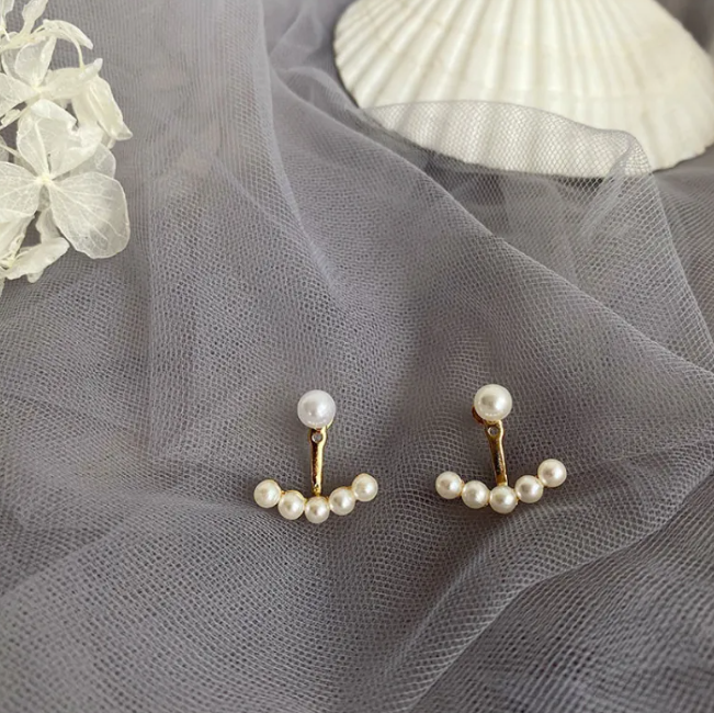 Pair of ear jacket earrings with a pearl-style stud and a curved row of pearl-style beads on grey tulle