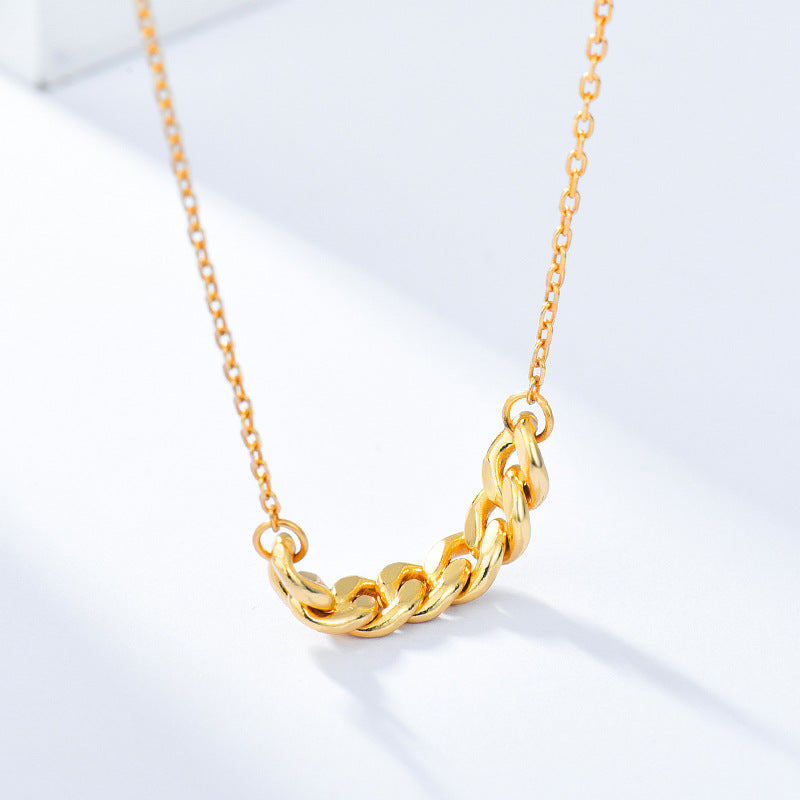 Gold-tone curb chain bar necklace close-up on a light surface