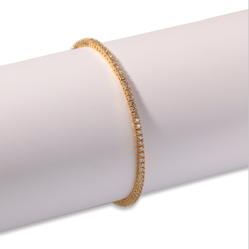 Gold-tone zirconia tennis bracelet on a white cylinder