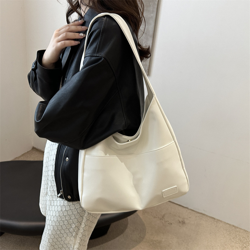 Woman in a black jacket carrying the cream slouchy shoulder bag on her shoulder