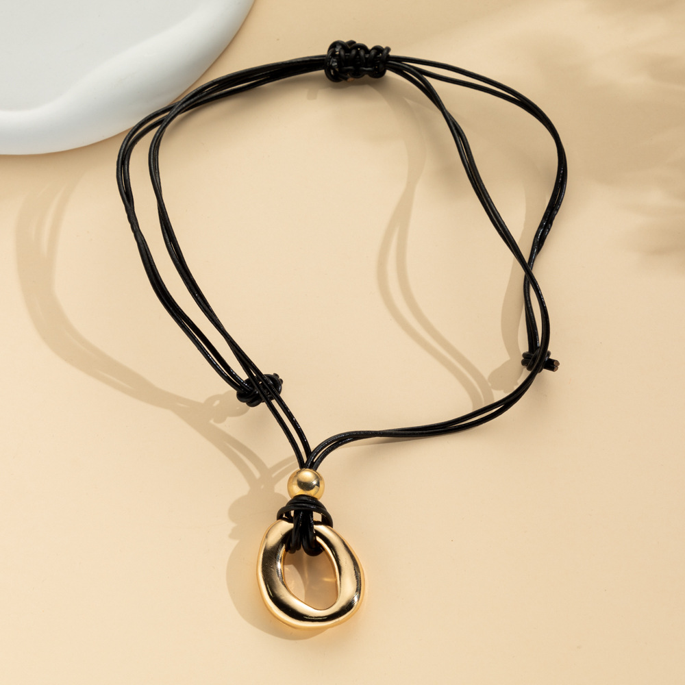 Gold-tone irregular circle pendant on a dark adjustable cord