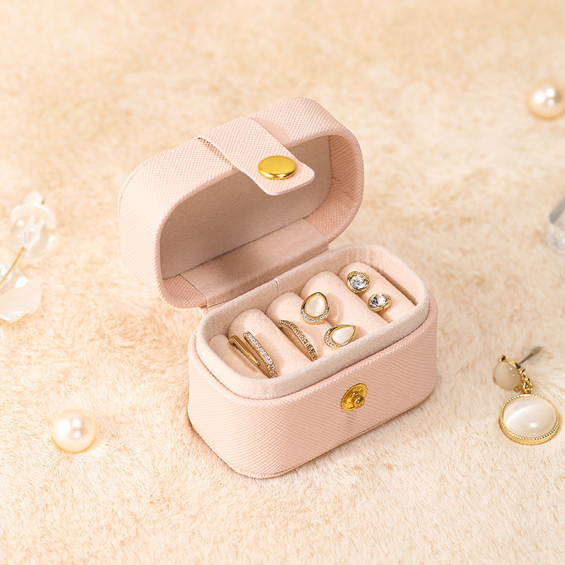 Pink mini ring travel case, open with gold-tone rings and stud earrings