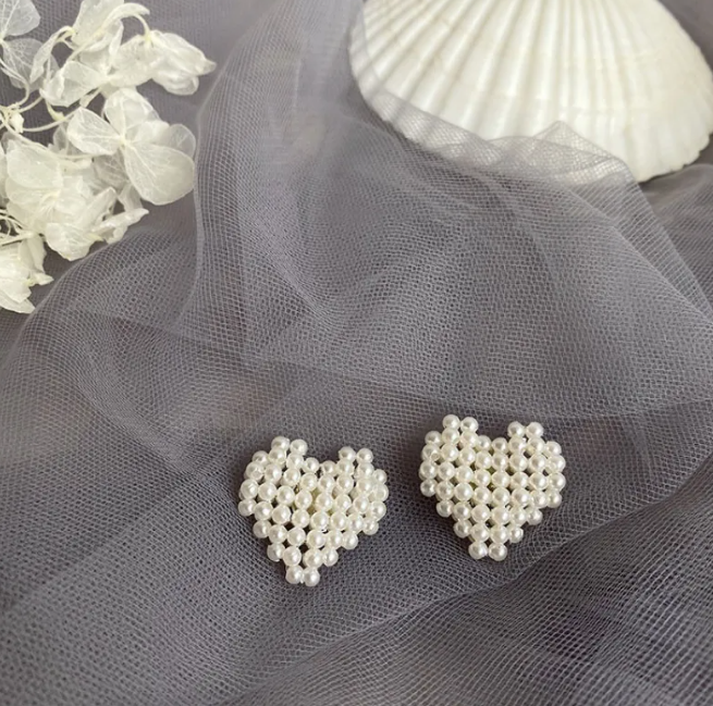 Pair of heart-shaped earrings woven from pearl-style beads on grey tulle